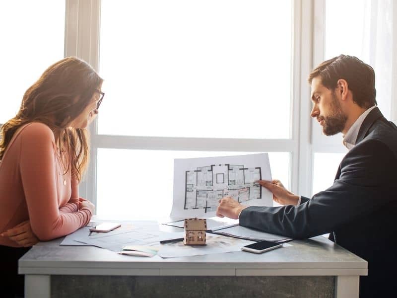 Professional explaining survey documents to a property owner while discussing land survey cost and planning considerations.