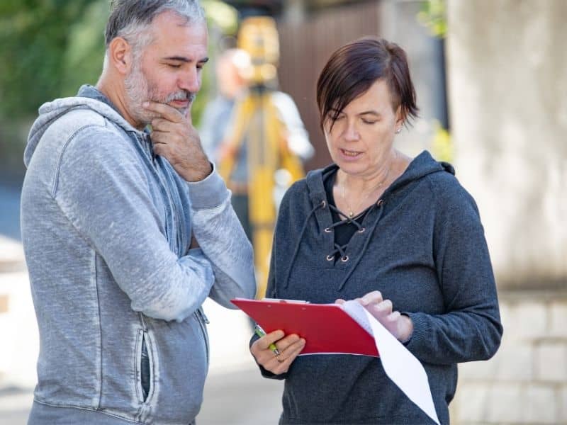 Homeowners reviewing documents during a property boundary survey with a licensed surveyor